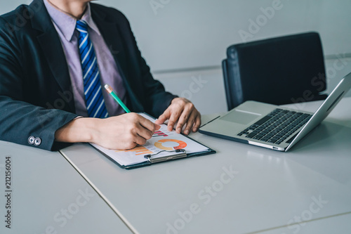 positive young business man sitting and working with documents and laptop,