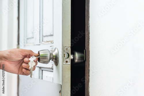 Foto unlocking and open decay wooden white door with key in hand