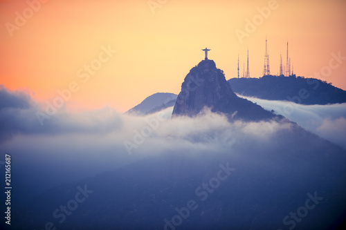 фотографія Silhouette of Corcovado mountain in golden sunset above swirling mist clouds Rio