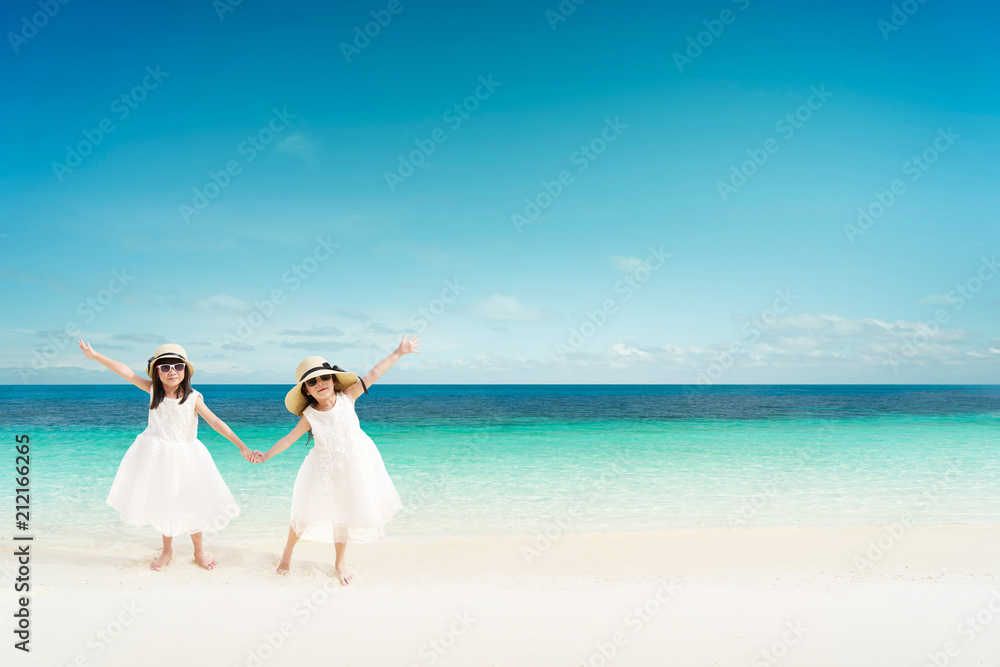 Portrait of happy asian sister at sandy beach in summer vacation .