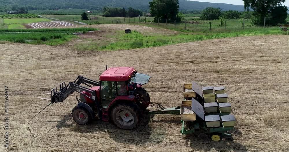 Aerial closeup tracking with tractor as it plants corn in a straw covered field with a corn planter. Aerial closeup tracking with tractor as it plants corn in a straw covered field with a corn planter.