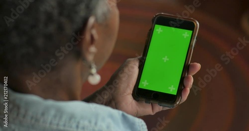 Older black woman looking at her smart phone with a chroma key greenscreen