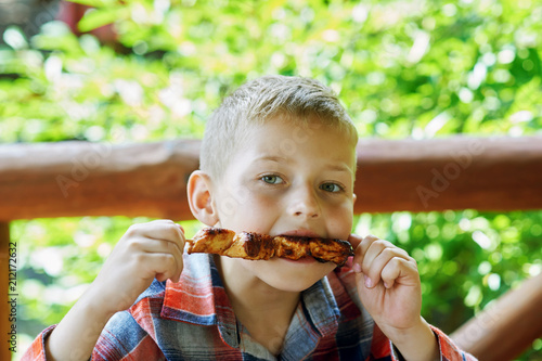 boy eating shish kebab at an outdoor cafe