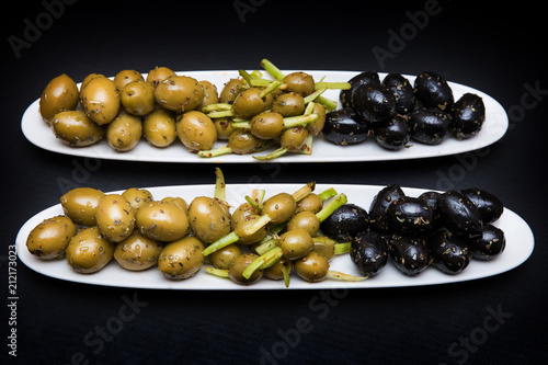 Fototapeta Naklejka Na Ścianę i Meble -  green and black olives on plates on a black background