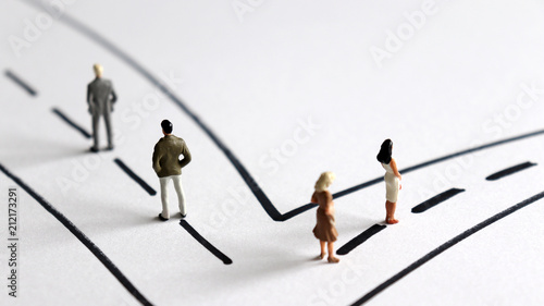 Two miniature men and two miniature women heading two different paths.