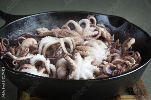 Mini octopus in the process of roasting on a cast iron pan