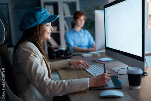 Young woman working overtime with graphic tablet in office.