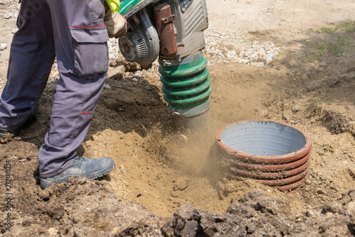 A worker with a vibrating machine compresses the sand