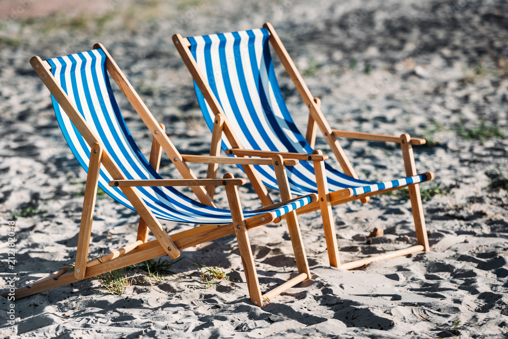 striped beach chairs and cooler on sandy coast striped beach chairs and cooler on sandy coast
