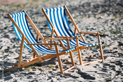 striped beach chairs and cooler on sandy coast