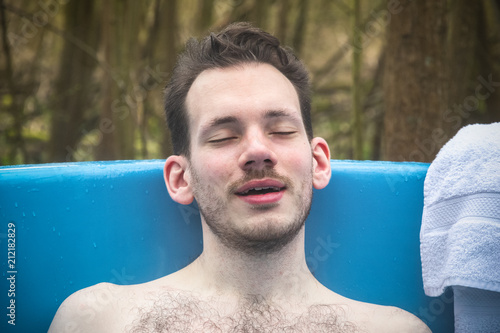 Man relaxing in an outdoor bath around a camping site in England photo