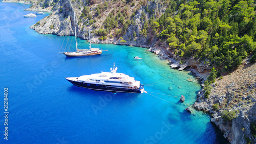 Aerial birds eye view photo taken by drone of famous tropical rocky beach of Nannou with yachts docked and clear turquoise waters, Symi island, Dodecanese, Greece