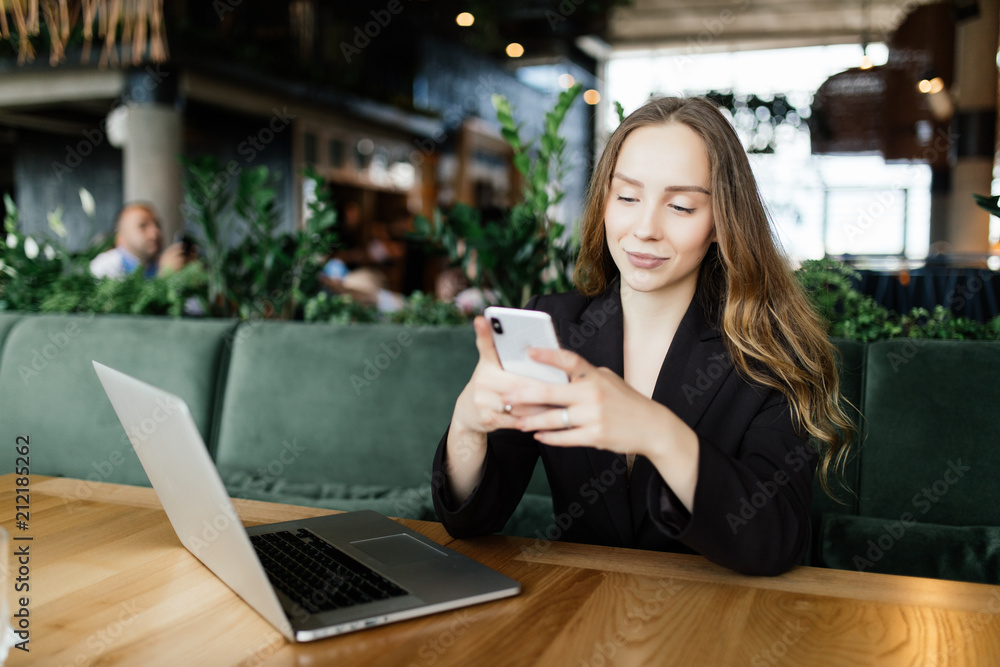 Beautiful brunette using laptop and mobile phone in cafe. Blogger work concept Beautiful brunette using laptop and mobile phone in cafe. Blogger work concept