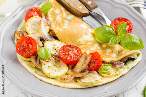Thin rolled omelet with fried vegetables, zucchini, tomato, onion, mushrooms, tasty healthy Breakfast,
