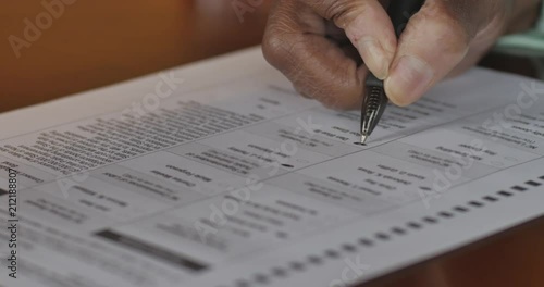 Senior black hand voting on a voter ballot in an election