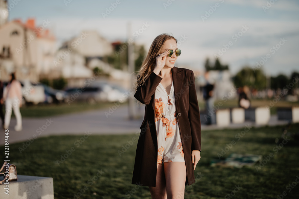 Close up image of happy woman in sunglasses clothes posing sideways outdoors