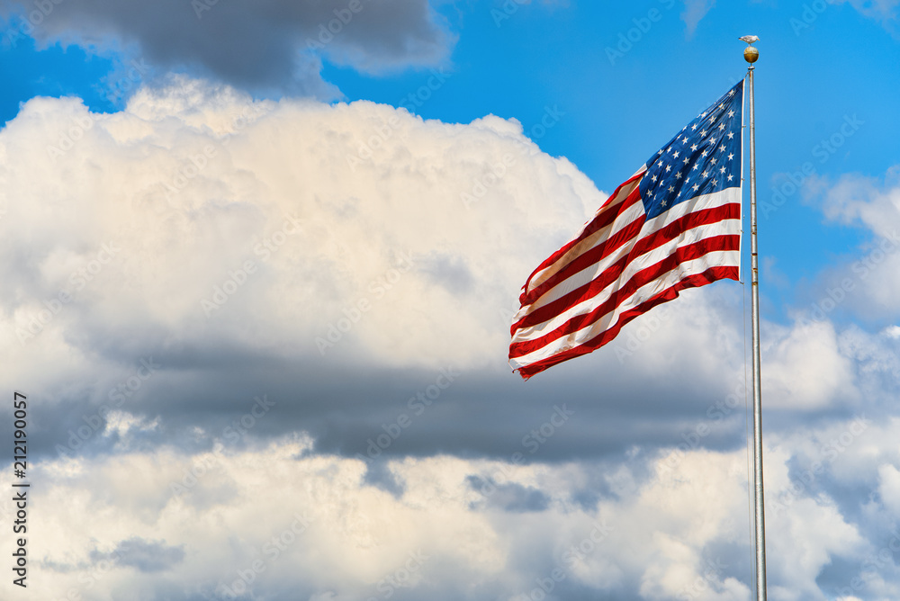 Star-striped American flag flutters proudly against the blue sky. Star-striped American flag flutters proudly against the blue sky.
