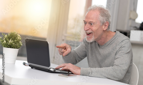 Happy mature man having a good surprise on laptop, light effect