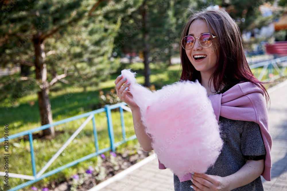Cheerful young pretty girl with a smile eats cotton candy Cheerful young pretty girl with a smile eats cotton candy