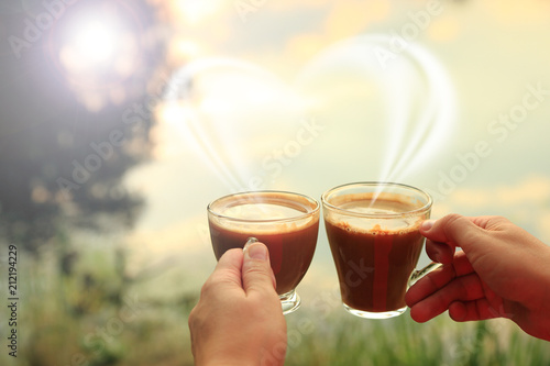 Dwie szklane filiżanki kawy w dłoniach kobiety przy zachodzie słońca.