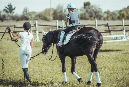 Obraz na plátně A little girl is learning to ride a horse.