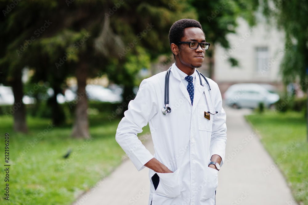 Stylish african american doctor with stethoscope and lab coat, at glasses posed outdoor. Stylish african american doctor with stethoscope and lab coat, at glasses posed outdoor.
