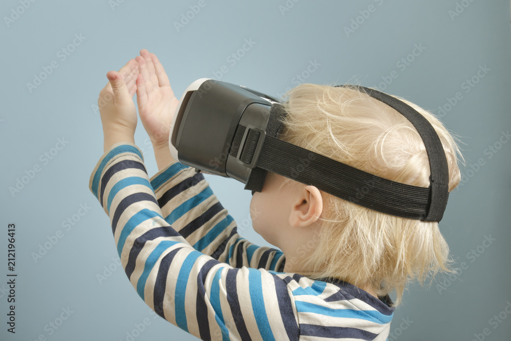 Little blond boy with glasses of virtual reality. Looks at the hands Little blond boy with glasses of virtual reality. Looks at the hands