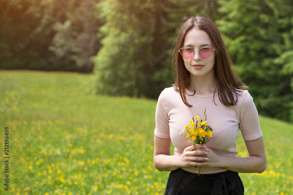 Young woman with bouquet of wildflowers on a sunny lawn. Summer day Young woman with bouquet of wildflowers on a sunny lawn. Summer day