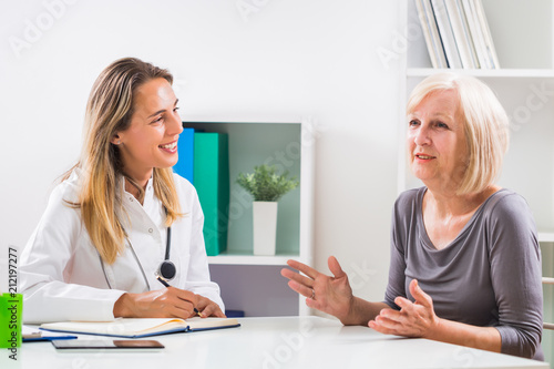 Female doctor and senior woman patient talking in doctor's office.