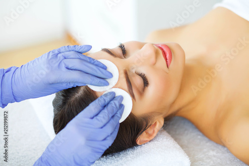 Beauty. Young Girl in Beauty Salon. Cosmetologist Cleans the Skin of the Face with Cotton Pads. Lying on the Massage Tables. Clean and Fresh Skin. Skin Care. High Resolution