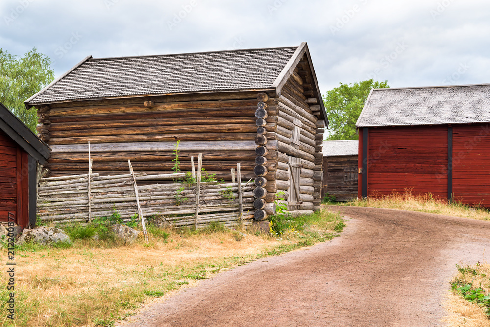 Traditional village storage building beside a country road passing some barns in the background. Location Stensjo in Smaland, Sweden. Traditional village storage building beside a country road passing some barns in the background. Location Stensjo in Smaland, Sweden.