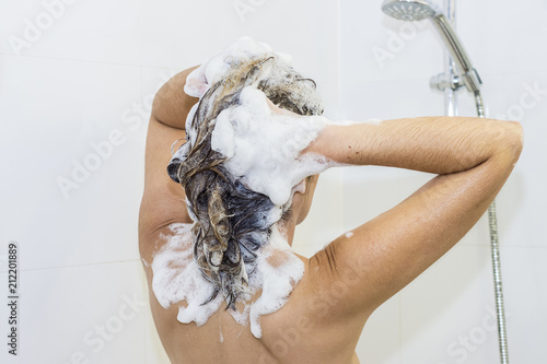 Lovely woman lathering her hair with shampoo in the shower