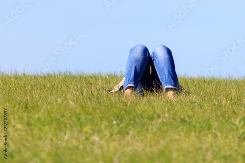 Legs of a girl in jeans on the grass