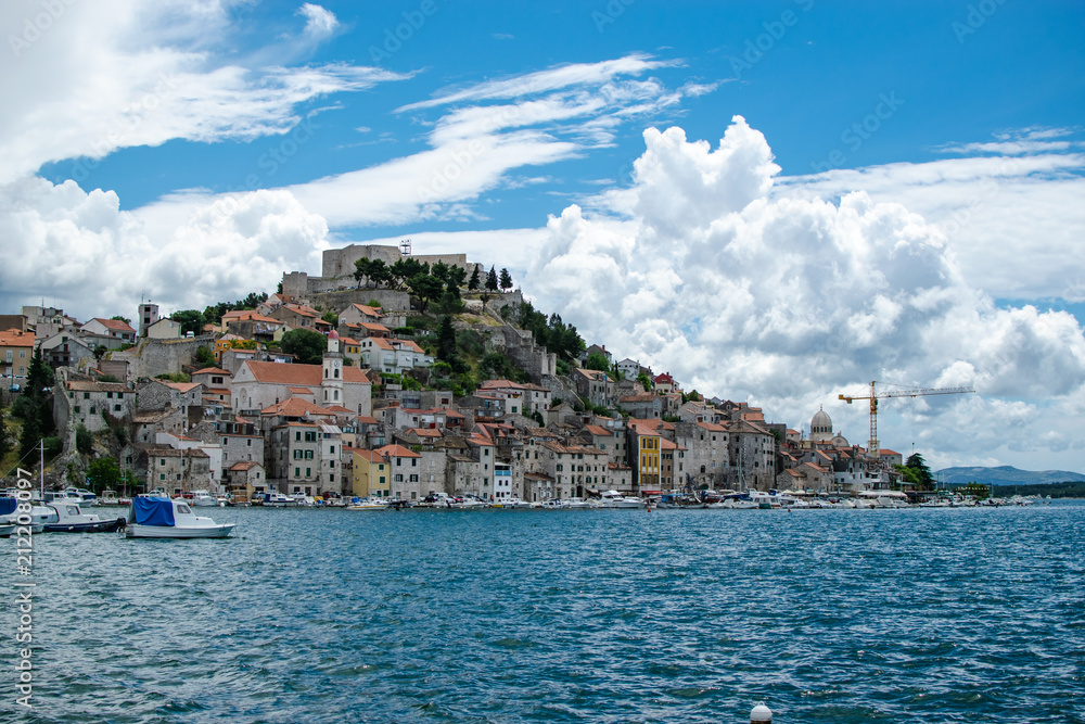 View from the seaport of the city to the center of it with all its monuments and in the background a beautiful sky full of clouds. Photograph taken in Sibenik in Croatia.