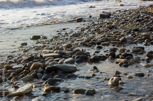 pebble stones on the sea beach, the rolling waves of the sea with foam © Wingedbull
