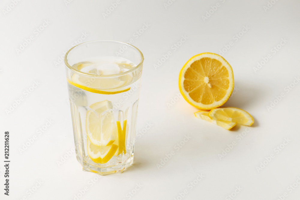 A glass of fresh cool water with lemon slices on a white background A glass of fresh cool water with lemon slices on a white background