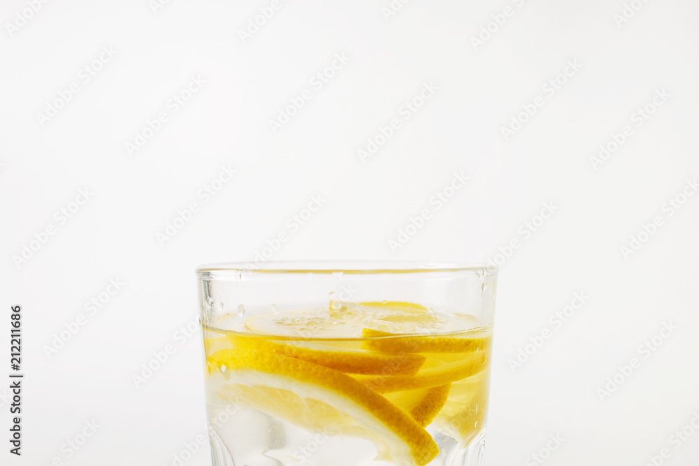 Refreshing water with lemon in a glass on a white background on a hot day Refreshing water with lemon in a glass on a white background on a hot day