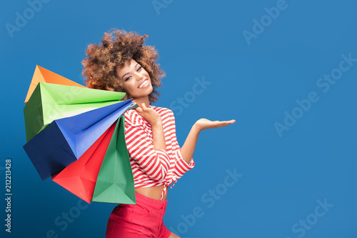 Happy afro girl holding colorful shopping bags.