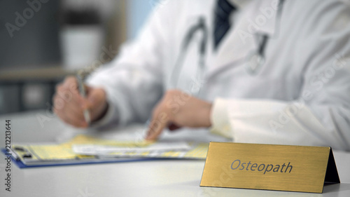 Attentive male osteopath chatting with patient on laptop, healthcare system photo