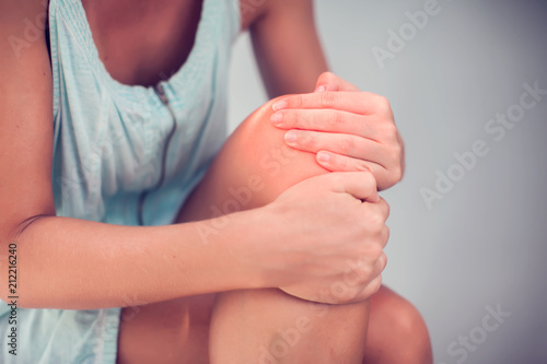 Closeup woman hand holding knee with pain on bed, health care and medical concept