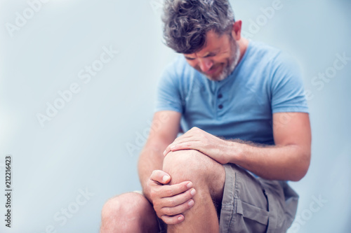 Closeup man hand holding knee with pain on bed, health care and medical concept