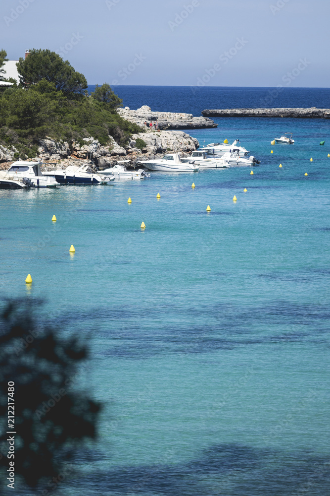 beautiful warm holiday in menorca island, spain. its clear turquoise sea water, sunny summer day and great vacation time with green trees surroundings