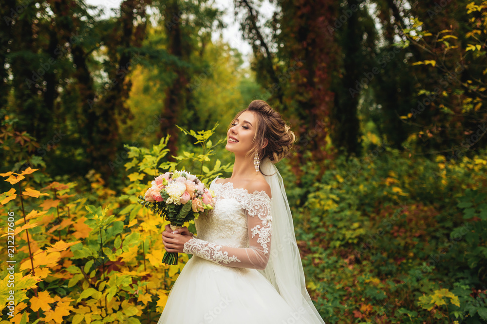 the bride with her eyes closed stands alone against the background of the autumn forest
