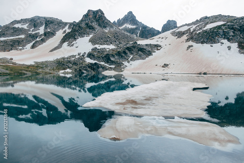 ice floe Drifts at mountain cold lake. snowy peaks reflected in water