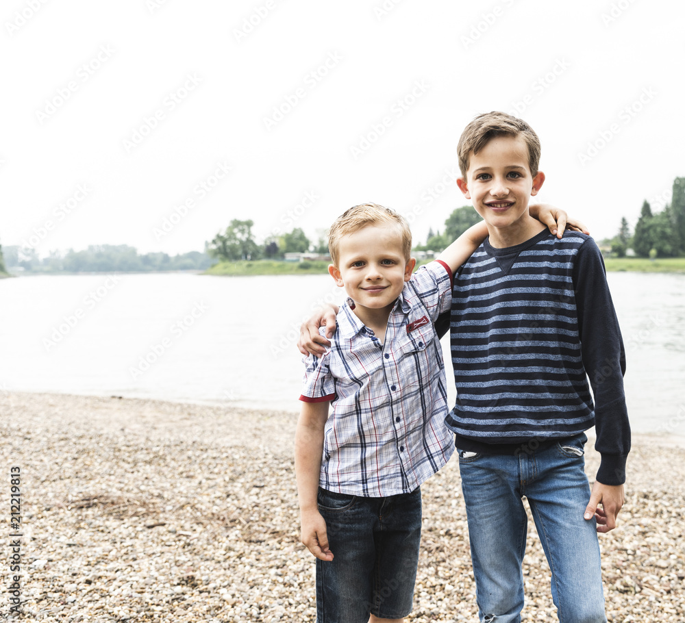 Portrait of two smiling boys embracing at the riverside