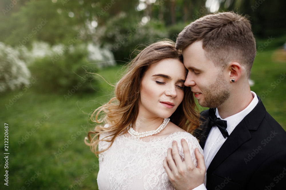 Elegant gorgeous bride and stylish groom posing in the park. 