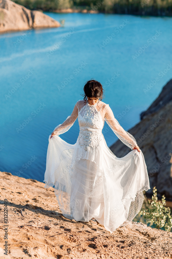 The bride in the evening sun at the edge of the cliff.