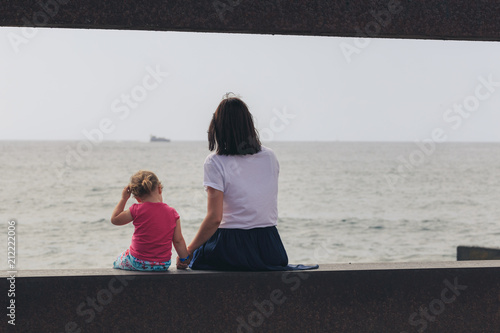 Obraz na płótnie Mother with little daughter looks at the sea. Back view. w salonie
