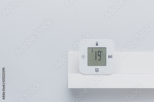 A white digital thermometer on the shelf with negative space. Room temperature concept.