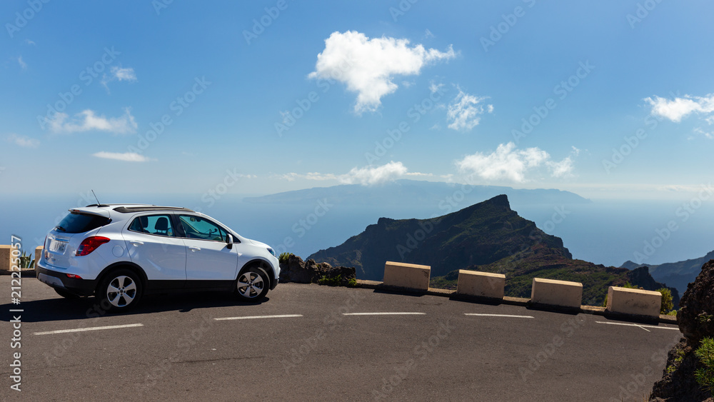 Sight on mountain and La Gomera island with white car on road, from Tenerife, near Masca village